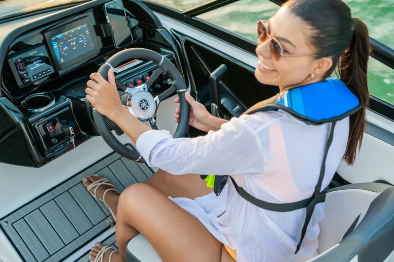 Slide: The Image of A woman sits at the helm of a Yamaha 195S boat, smiling and wearing sunglasses. - 13