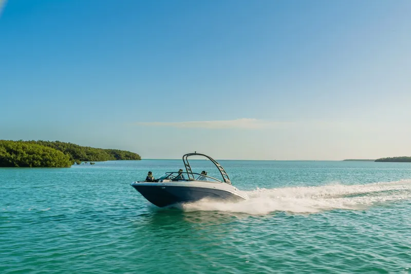 Slide: The Image of A 2024 Yamaha 195S boat speeds across blue water under a clear sky. - 32