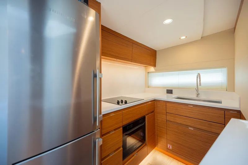 Slide: The Image of Modern kitchen interior in 2022 Bertram 50 Sport yacht, featuring sleek wood cabinetry and stainless steel appliances. - 21