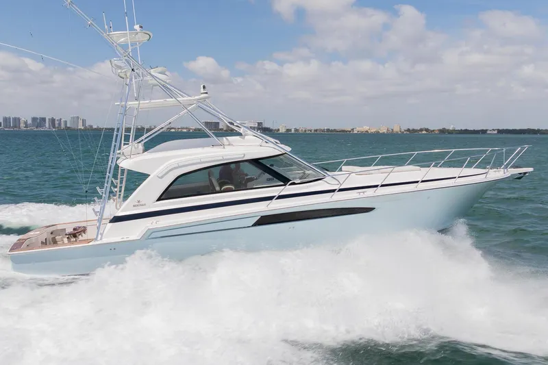 Slide: The Image of 2022 Bertram 50 Sport yacht cruising on ocean with city skyline in background. - 2