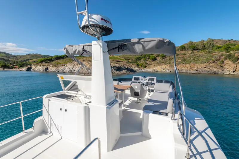 Slide: The Image of 2026 Beneteau Swift Trawler 41 Flybridge, scenic coastal view, clear blue water. - 23