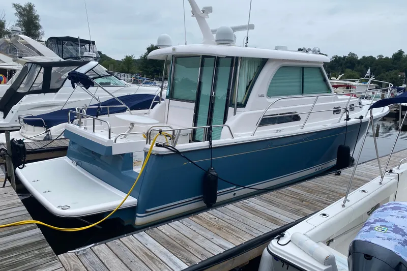 The Image of 2014 Sabre 38 Salon Express yacht docked at marina, featuring sleek blue and white design. - 0