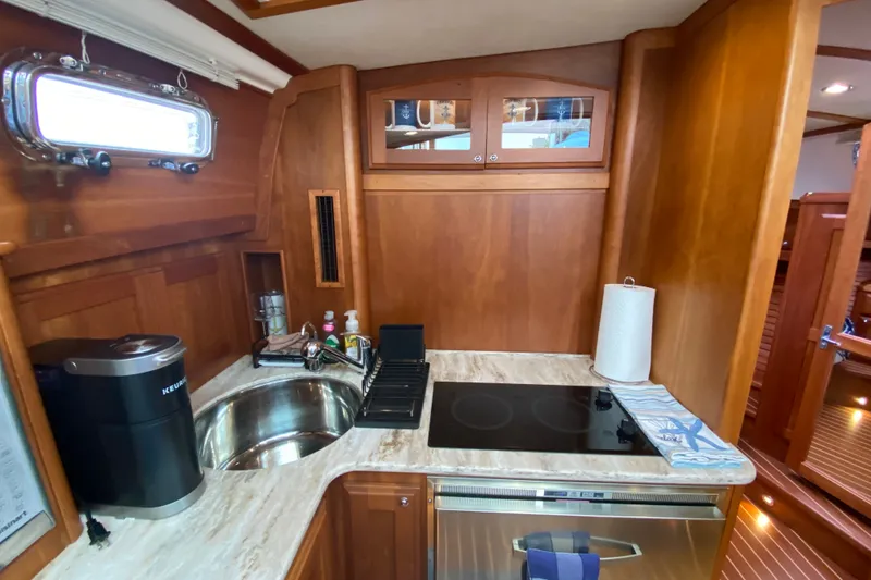Slide: The Image of 2014 Sabre 38 Salon Express galley with sink, stove, and wooden cabinetry. - 18