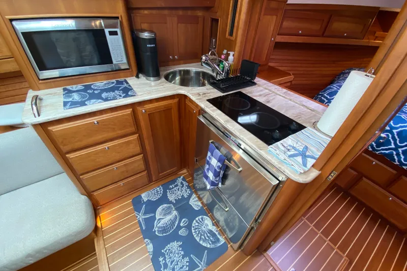Slide: The Image of 2014 Sabre 38 Salon Express galley with wood cabinetry, microwave, and cooktop. - 17
