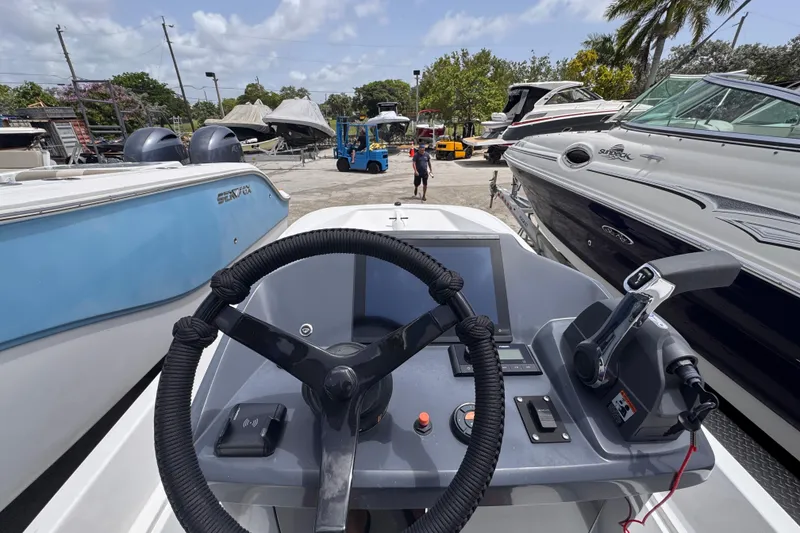 Slide: The Image of 1980 Boston Whaler 17 Montauk dashboard view at a boatyard with surrounding vessels. - 14