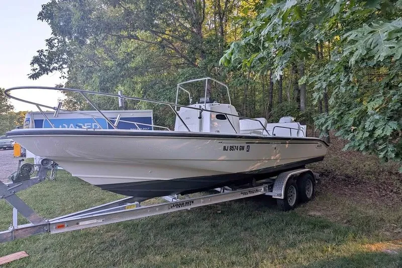 Slide: The Image of 2004 Boston Whaler 220 Dauntless boat on trailer, parked near trees. - 8