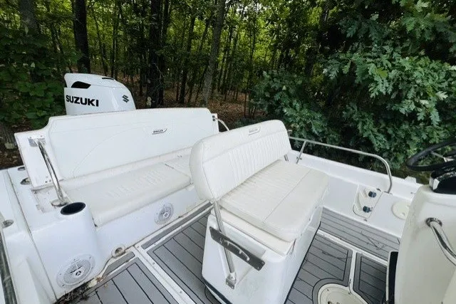 Slide: The Image of 2004 Boston Whaler 220 Dauntless boat interior with Suzuki engine, surrounded by lush greenery. - 5