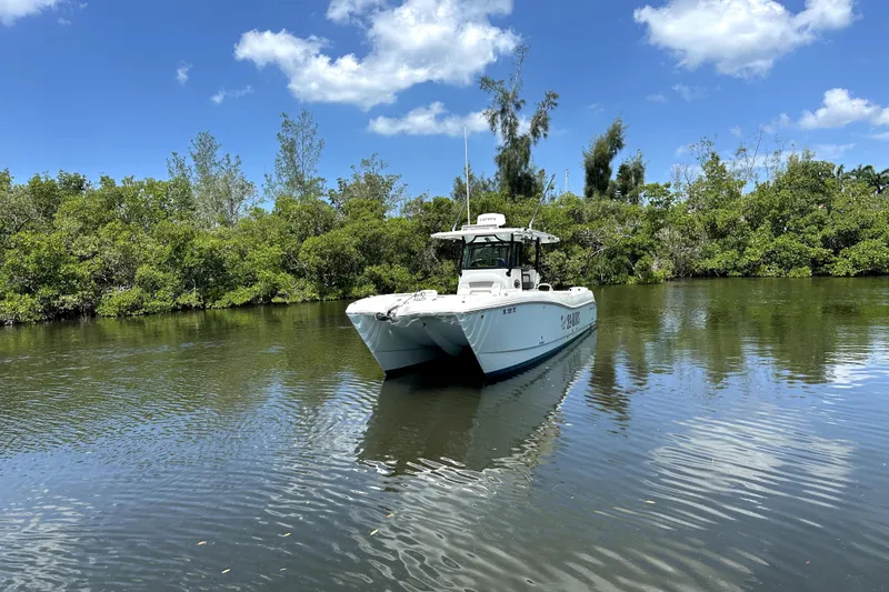 Slide: The Image of 2022 World Cat 325 CC boat on calm water, surrounded by lush greenery and blue sky. - 17