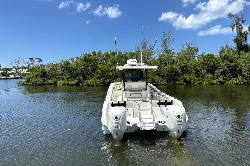 Slide: The Image of 2022 World Cat 325 CC boat on water, surrounded by lush greenery. - 2