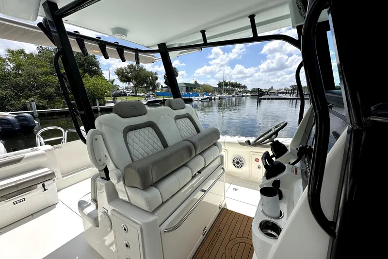 Slide: The Image of 2022 World Cat 325 CC boat interior with helm, seating, and marina view. - 16