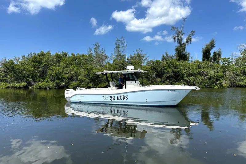 Slide: The Image of 2022 World Cat 325 CC boat on calm water, surrounded by lush greenery. - 1