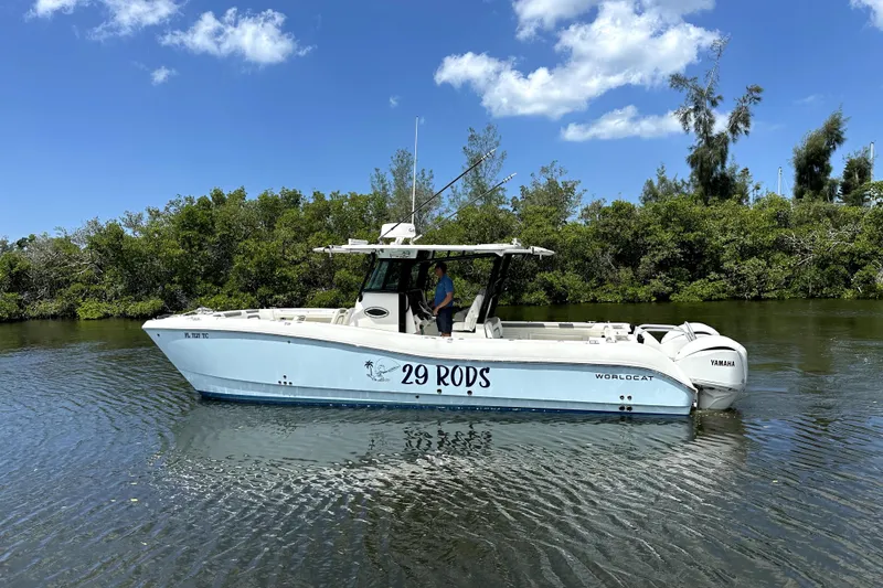 The Image of 2022 World Cat 325 CC boat on calm water, surrounded by lush greenery and clear blue sky. - 0
