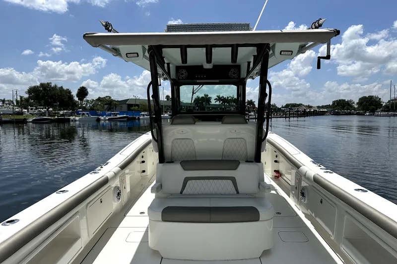 Slide: The Image of 2022 World Cat 325 CC boat interior with seating, on a calm waterway under a blue sky. - 14