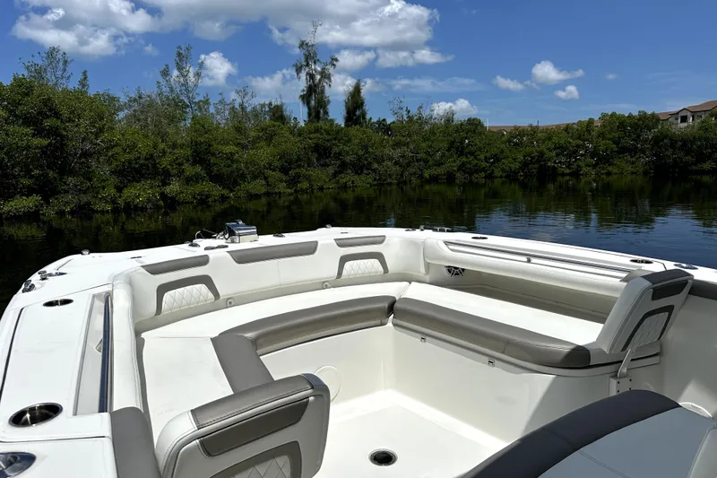 Slide: The Image of 2022 World Cat 325 CC boat interior with plush seating, surrounded by serene water and greenery. - 6