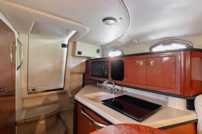 Slide: The Image of 2005 Sea Ray 270 Amberjack interior with kitchenette, featuring wood cabinets and modern appliances. - 20