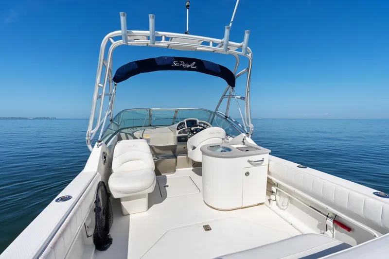 Slide: The Image of 2005 Sea Ray 270 Amberjack boat interior with seating and helm, on calm blue water. - 12