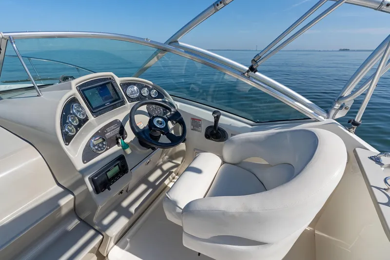 Slide: The Image of 2005 Sea Ray 270 Amberjack helm with steering wheel and navigation controls on open water. - 17