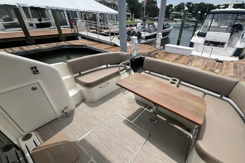 Slide: The Image of 2019 Carver C37 yacht deck with seating and wooden table at marina. - 19