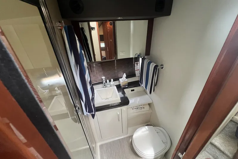Slide: The Image of Compact bathroom in a 2019 Carver C37 yacht with sink, toilet, and striped towels. - 37