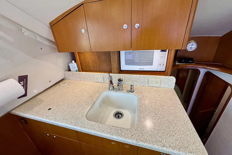 Slide: The Image of 1999 Ocean Yachts 45 Super Sport galley with sink, microwave, and wooden cabinetry. - 14