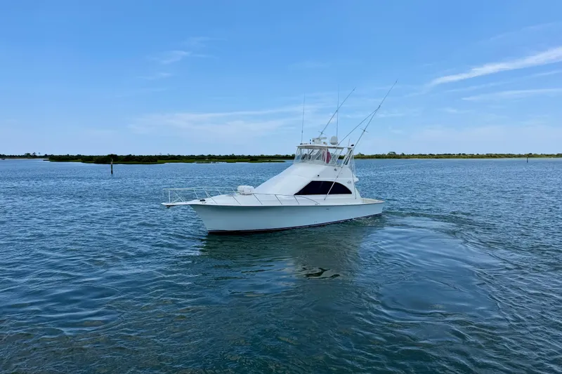 Slide: The Image of 1999 Ocean Yachts 45 Super Sport cruising on calm waters under a clear blue sky. - 4