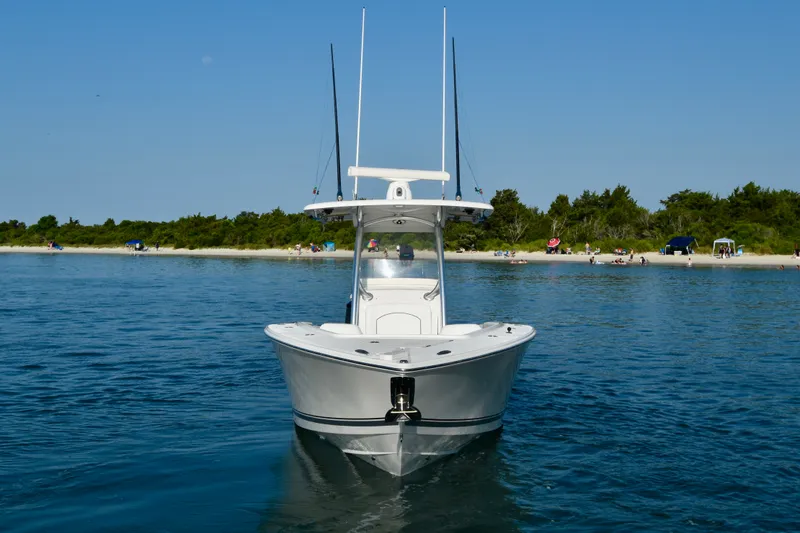 Slide: The Image of A white 2015 Jupiter Center Console boat on calm water near a wooded shoreline. - 6
