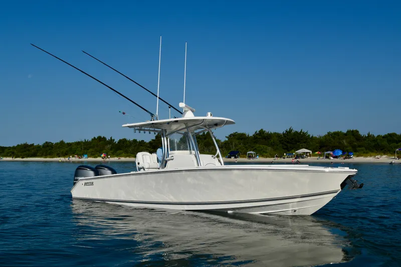 Slide: The Image of A white 2015 Jupiter Center Console boat on calm water near a beach. - 7