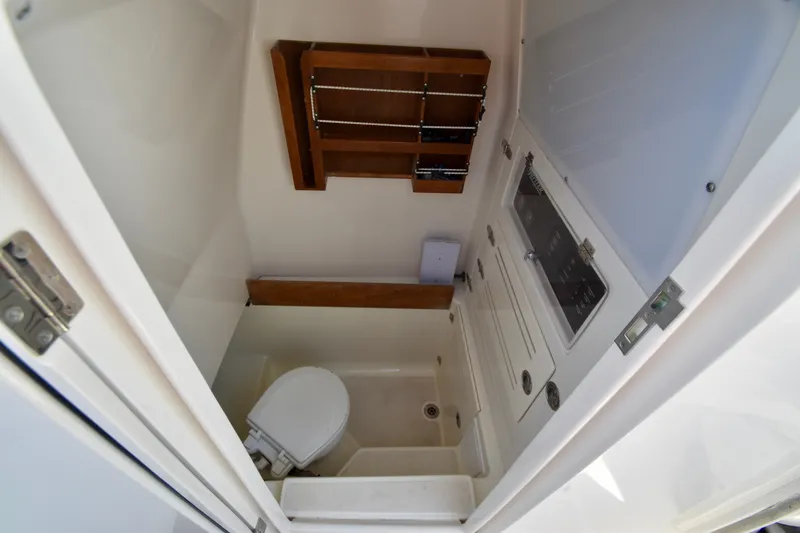 Slide: The Image of The image shows a compact boat cabin with a toilet and wooden shelf. - 39