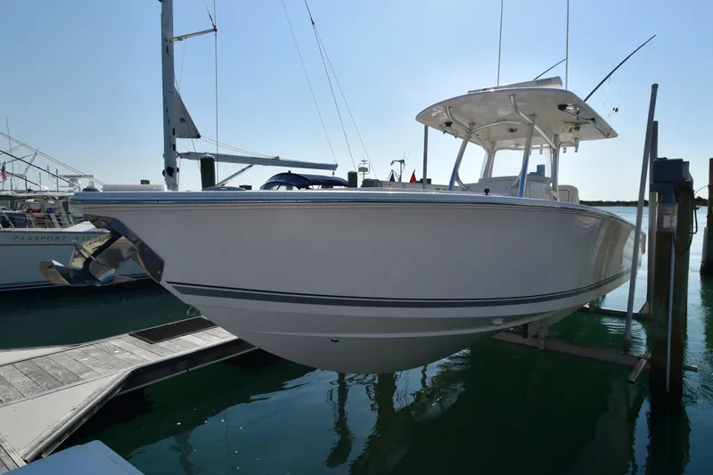 Slide: The Image of A 2015 Jupiter Center Console boat is on a lift above the water. It features a sleek design. - 31