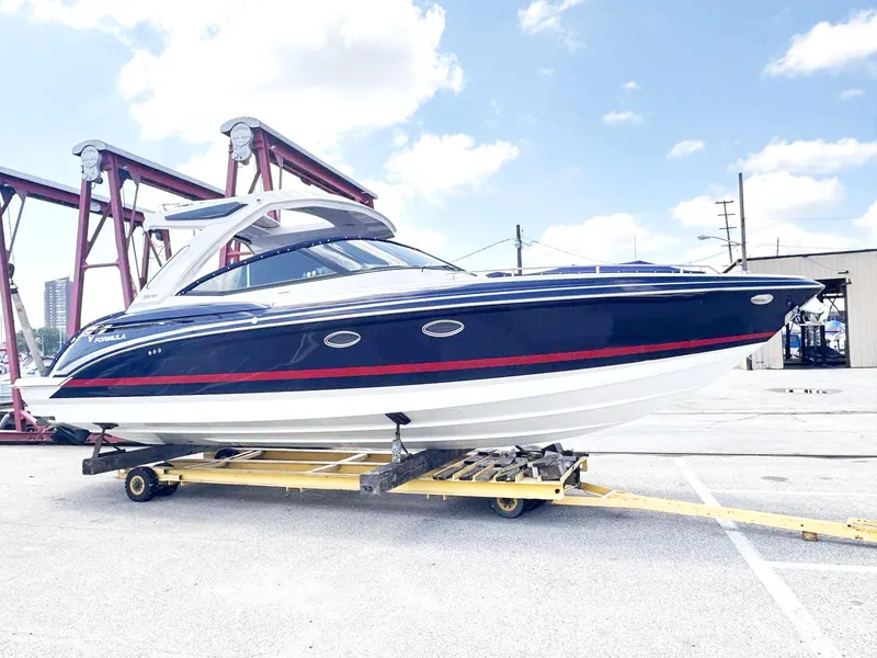 Slide: The Image of A sleek blue and white boat with a red stripe sits on a trailer in a harbor area. - 1