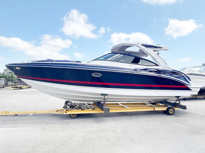Slide: The Image of A sleek blue and white boat with a red stripe sits on a trailer under a blue sky. - 0