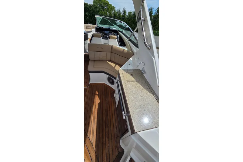 Slide: The Image of 2016 Sea Ray SLX 350 boat interior with tan seating and wooden flooring. - 16