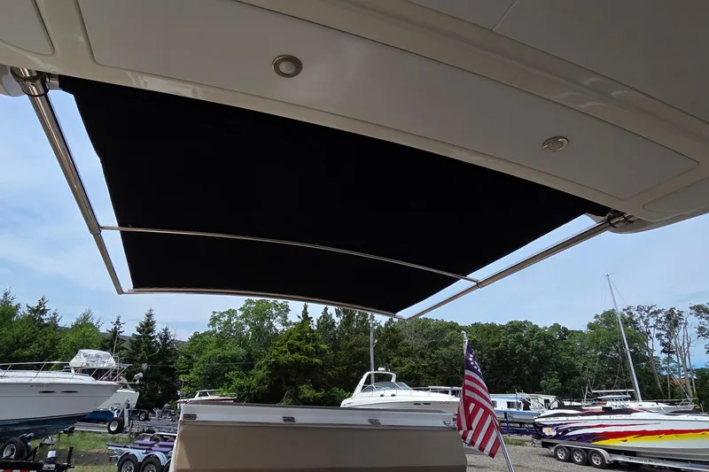 Slide: The Image of 2016 Sea Ray SLX 350 boat with extended sunshade, docked near other boats. - 18
