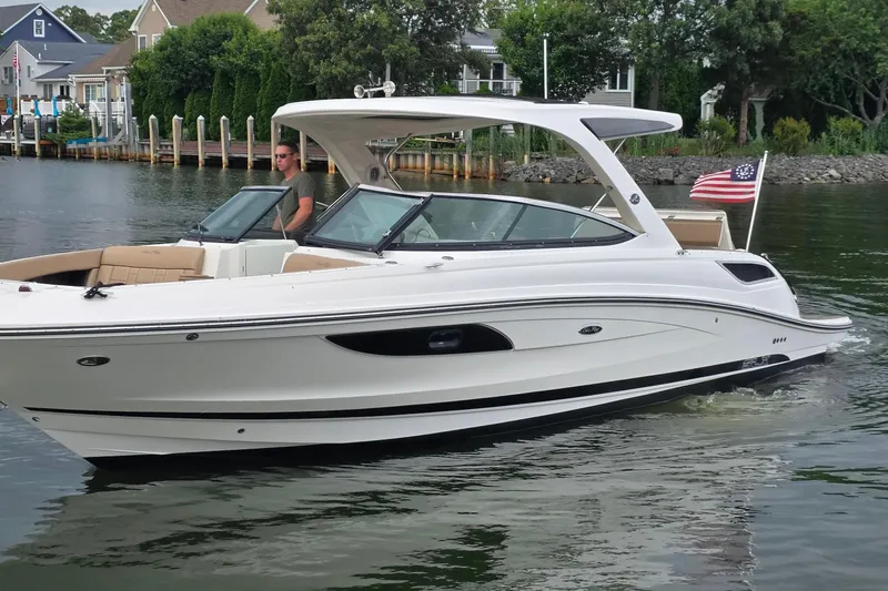 The Image of 2016 Sea Ray SLX 350 boat cruising on a calm waterway with American flag. - 0