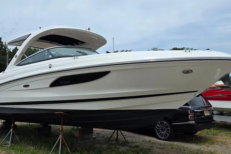 Slide: The Image of 2016 Sea Ray SLX 350 boat on stands, parked beside a Range Rover. - 2