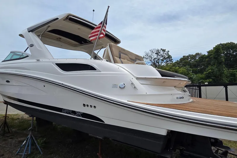 Slide: The Image of 2016 Sea Ray SLX 350 boat with American flag, docked outdoors, side view. - 3