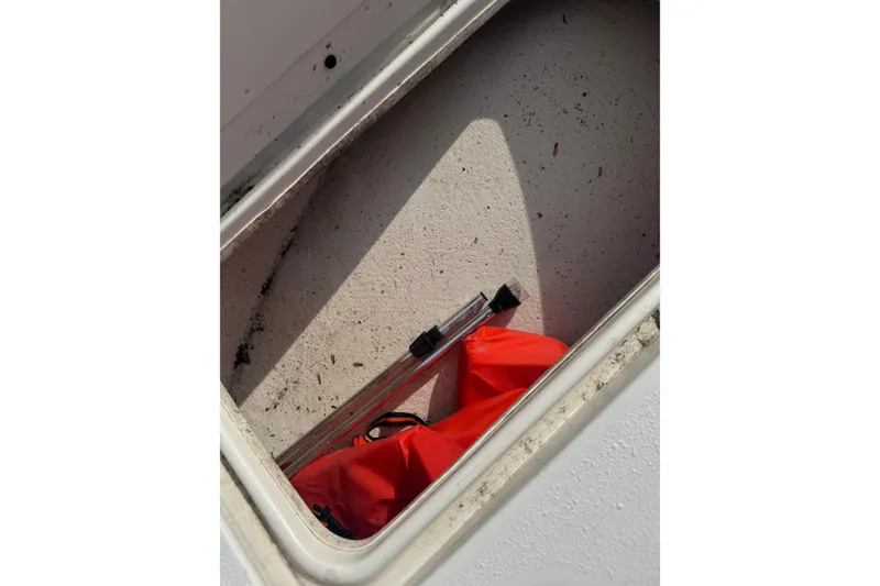Slide: The Image of Storage compartment of a 2014 Carolina Skiff 198 DLV with red bag and metal rod. - 20