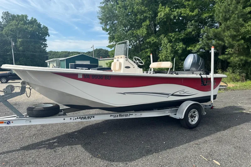 The Image of 2014 Carolina Skiff 198 DLV boat on trailer, parked outdoors with trees in background. - 1