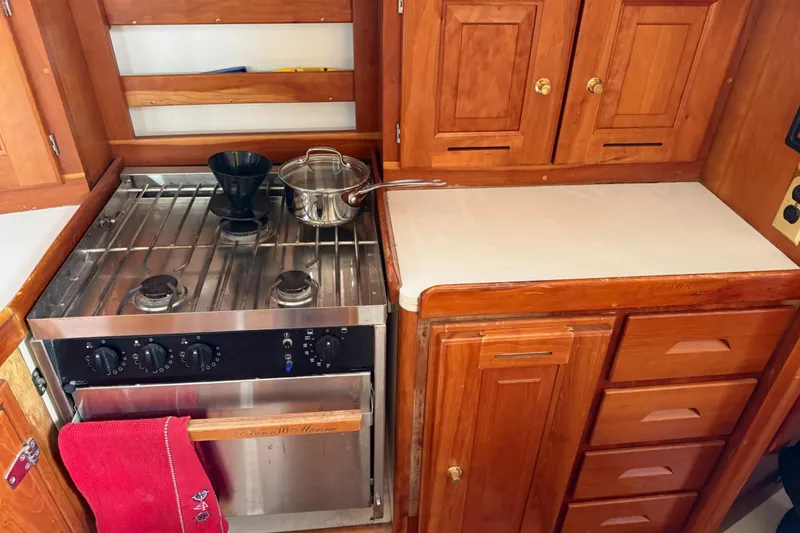 Slide: The Image of Wooden boat kitchen with stove, pot, and cabinets in a 2000 Tartan 3700 model. - 17