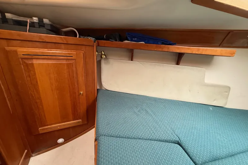 Slide: The Image of Cozy cabin interior of 2000 Tartan 3700 sailboat with wooden cabinetry and blue cushions. - 14
