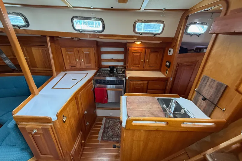 Slide: The Image of Interior of a 2000 Tartan 3700 sailboat featuring a wooden galley kitchen. - 16