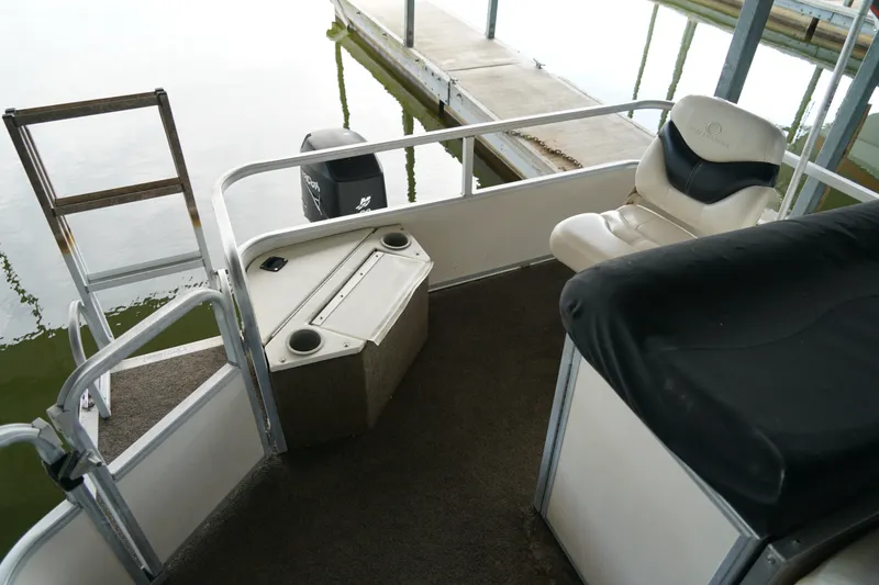 Slide: The Image of 2005 Sun Tracker Fishin' Barge 21 interior with seating and ladder near dock. - 14