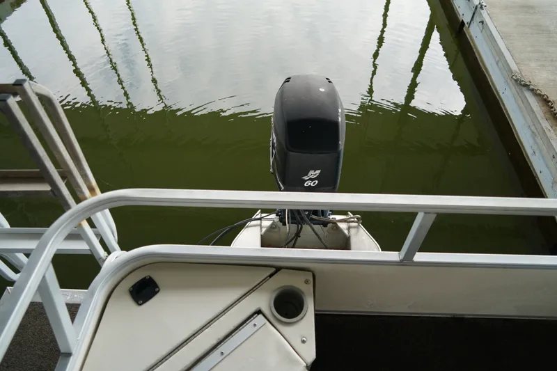 Slide: The Image of 2005 Sun Tracker Fishin' Barge 21 Signature Series with outboard motor on calm water. - 15