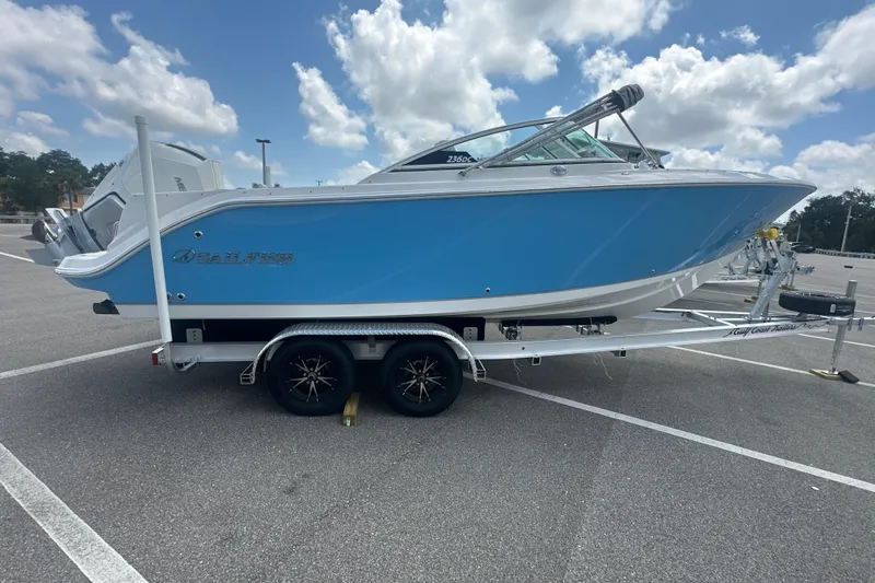 Slide: The Image of 2026 Sailfish 236 DC boat on trailer, blue hull, parked in lot under cloudy sky. - 14