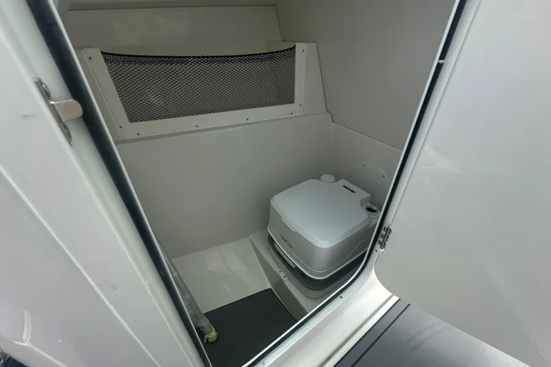Slide: The Image of Interior of 2026 Sailfish 236 DC boat featuring a compact marine toilet. - 34