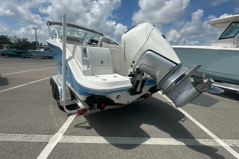 Slide: The Image of 2026 Sailfish 236 DC boat on trailer, featuring powerful outboard motor, parked under cloudy sky. - 29