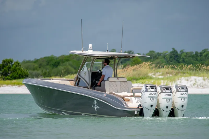 Slide: The Image of 2015 Statement 380 Open boat cruising with four engines, near a lush shoreline. - 2