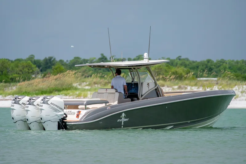 The Image of 2015 Statement 380 Open boat with triple Mercury engines cruising near a lush shoreline. - 0