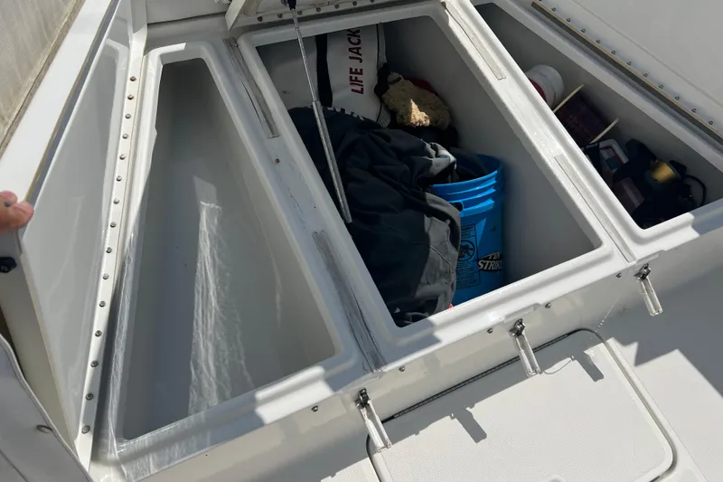 Slide: The Image of Open storage compartments on a 2002 Triton 2895 CC boat, containing various boating supplies. - 5