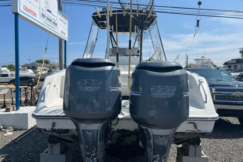 Slide: The Image of 2002 Triton 2895 CC boat with twin 225 horsepower engines at a marina. - 2